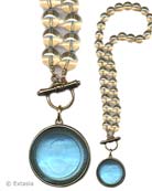 Transparent Aqua German Glass intaglio pendant on Champagne Czech glass hand knotted beading. Large pendant is 1 1/2 inches in diameter on 17 inch long beaded necklace. Front toggle closure. Shown in our signature Bronze metal. Each necklace made to order in the USA from the worlds finest materials.
